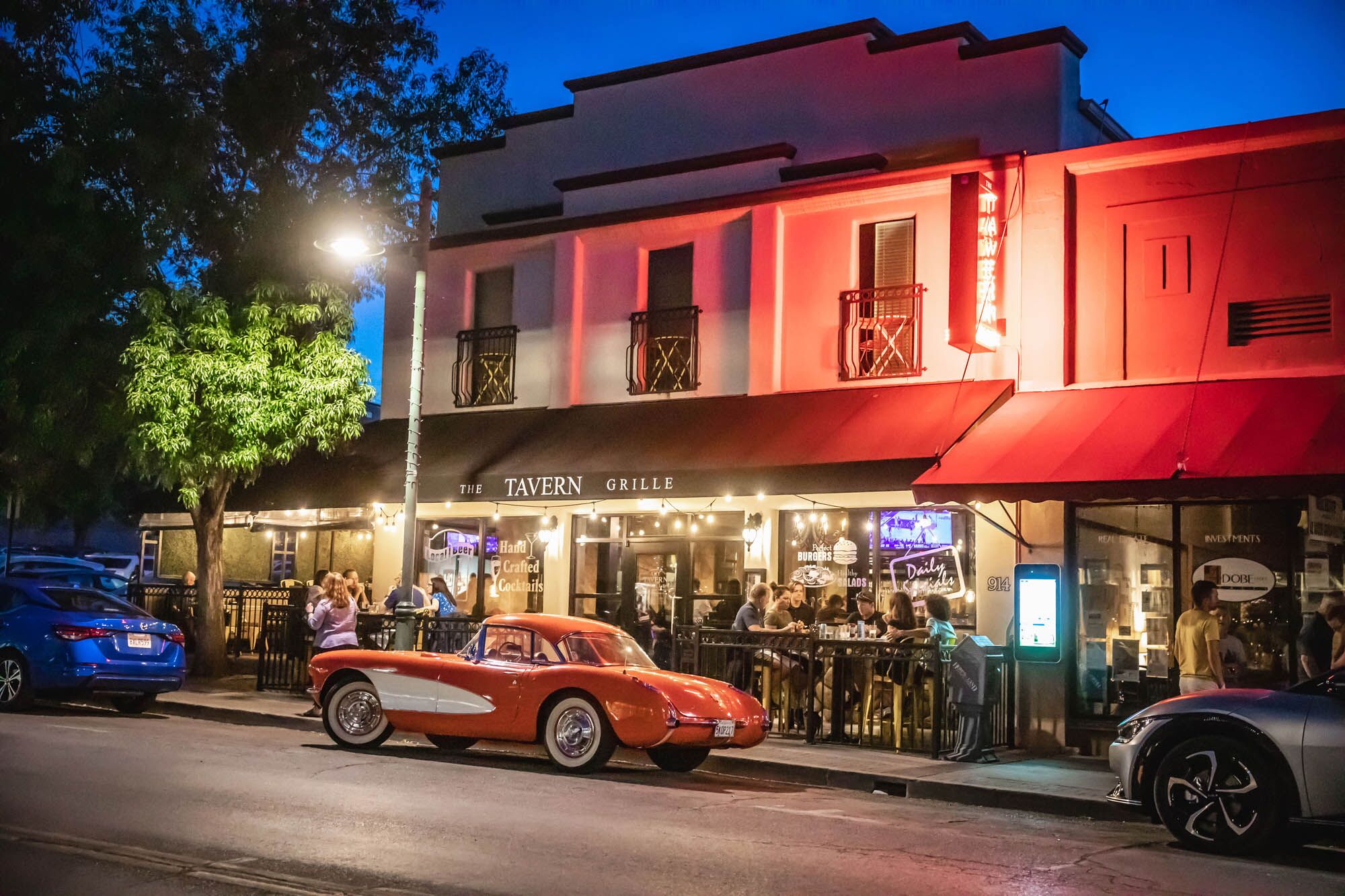 Tavern in Old Town Cottonwood Vintage red car parked outside lively evening tavern with patrons dining